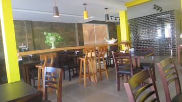 A restaurant interior with wooden tables and chairs, a bar area, and a decorative plant.