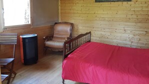 A wooden cabin room with a bed, a chair, and a table. - LES TRUFFIERS Cabane (Limans)