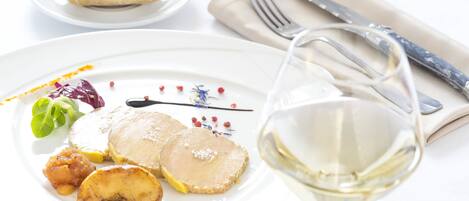 A plate with food and a glass of white wine.