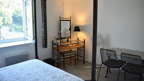 A bedroom with a bed, a desk with a chair, a mirror, a lamp, and a window with curtains. - Le Trianon de Salies (Salies-de-Bearn)