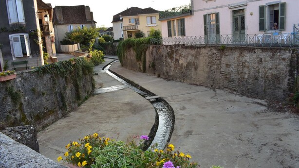 A narrow alleyway with buildings on either side, featuring stone walls and a small water channel. - Le Trianon de Salies (Salies-de-Bearn)