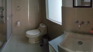 A bathroom with a toilet, sink, and shower area. - Coriñawi Apartment for Rent (Cusco)