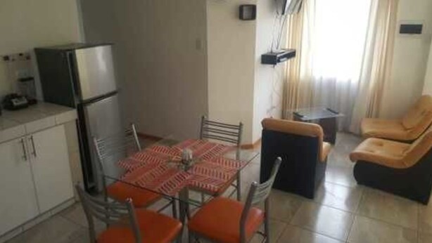 A compact living space with a kitchenette, dining table, and seating area. - Coriñawi Apartment for Rent (Cusco)