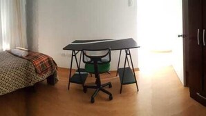 A room with a bed, a desk with a chair, and a wardrobe. - Coriñawi Apartment for Rent (Cusco)