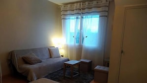 Una habitación pequeña y acogedora con un sofá, una mesita y una cama.