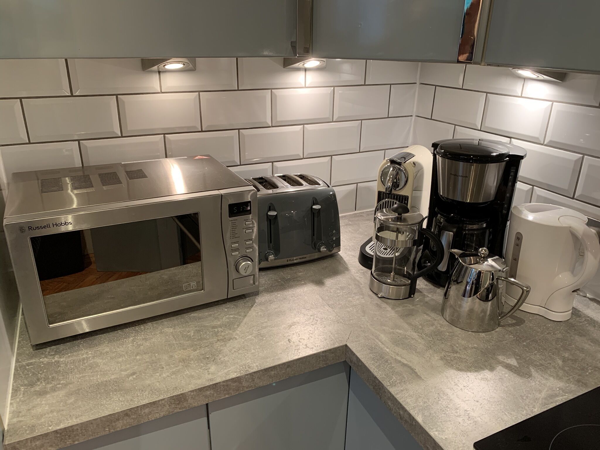 Une cuisine équipée d’un four à micro-ondes, d’un grille-pain, d’une machine à café et d’une bouilloire, le tout posé sur un plan de travail.