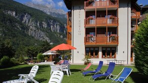 A hotel with a balcony, outdoor seating, and a mountainous backdrop. - Hotel Zurigo (Molveno)