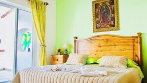 Un lit avec une tête de lit en bois, un mur vert et un tableau encadré au-dessus.