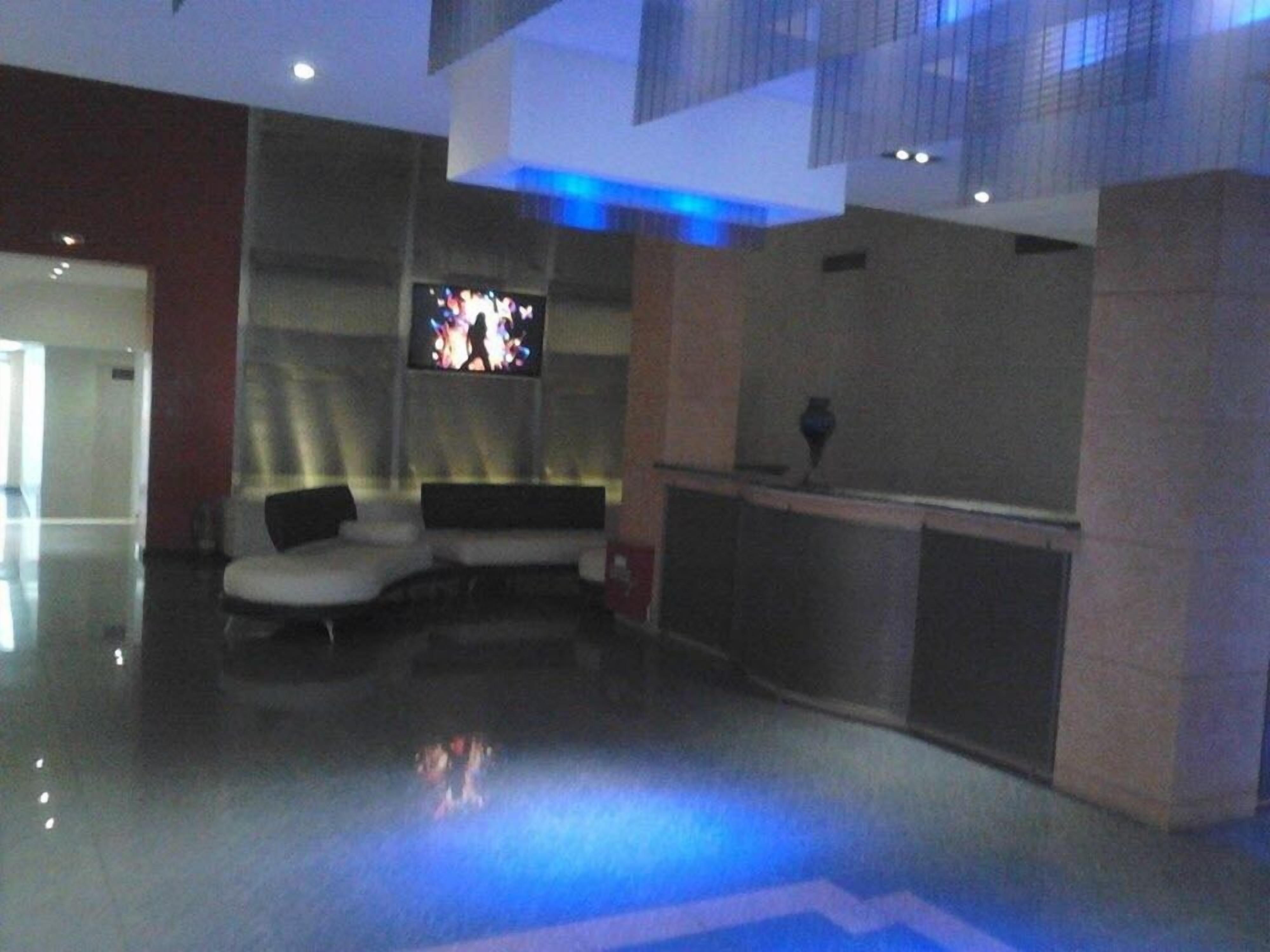 Un vestíbulo moderno con zona de estar, un televisor de pantalla plana en la pared y un mostrador de recepción.