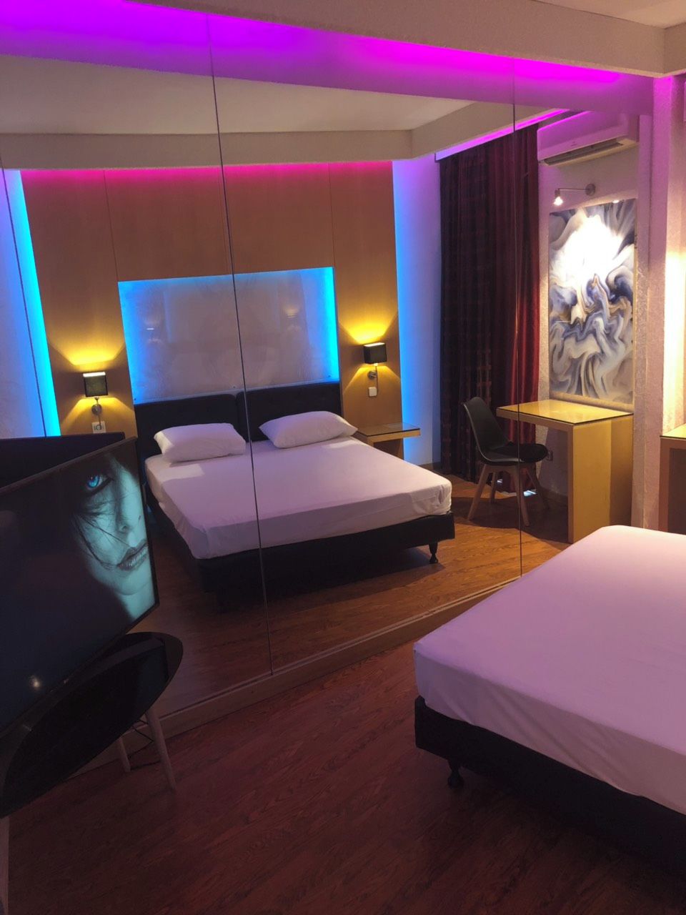 Quarto de hotel com duas camas, uma escrivaninha e uma cadeira.