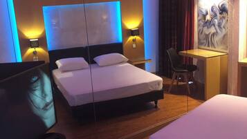 Quarto de hotel com duas camas, uma escrivaninha e uma cadeira.