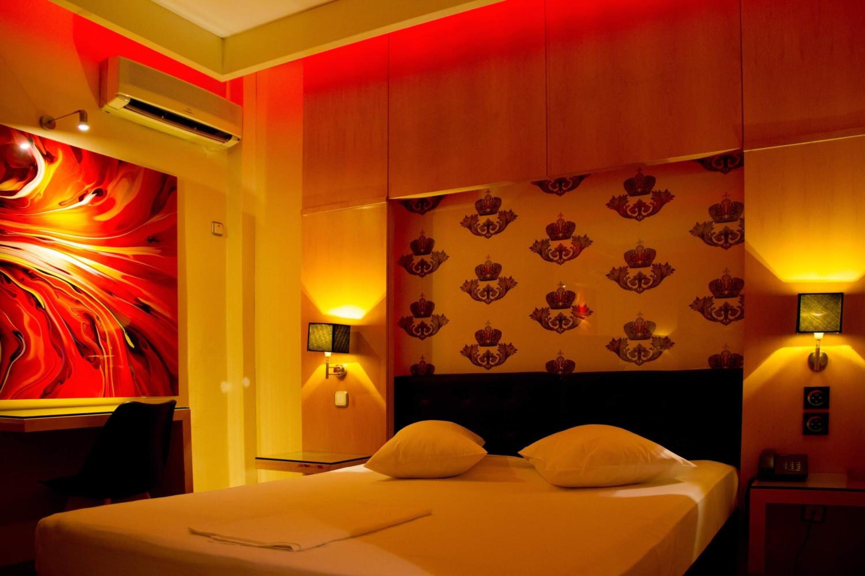 Une chambre d’hôtel avec un grand lit, un bureau et une fresque murale abstraite aux couleurs vives.