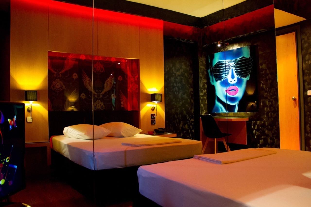 A hotel room with two beds, a desk, and a large mirror.