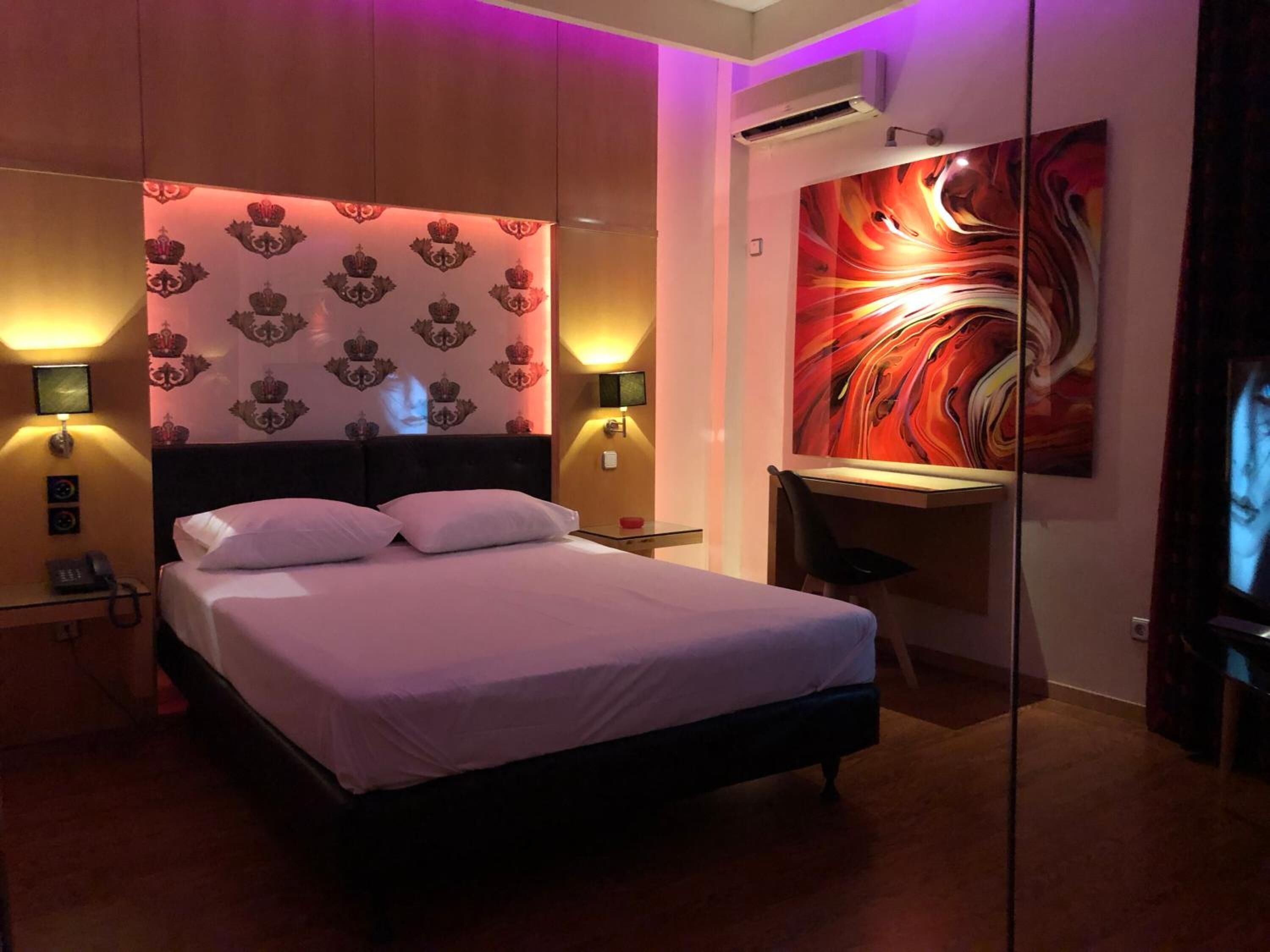 Una habitación de hotel con una cama, un escritorio y un espejo grande.