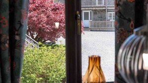 Una ventana con cortinas, un florero y una pequeña escultura en el alféizar.