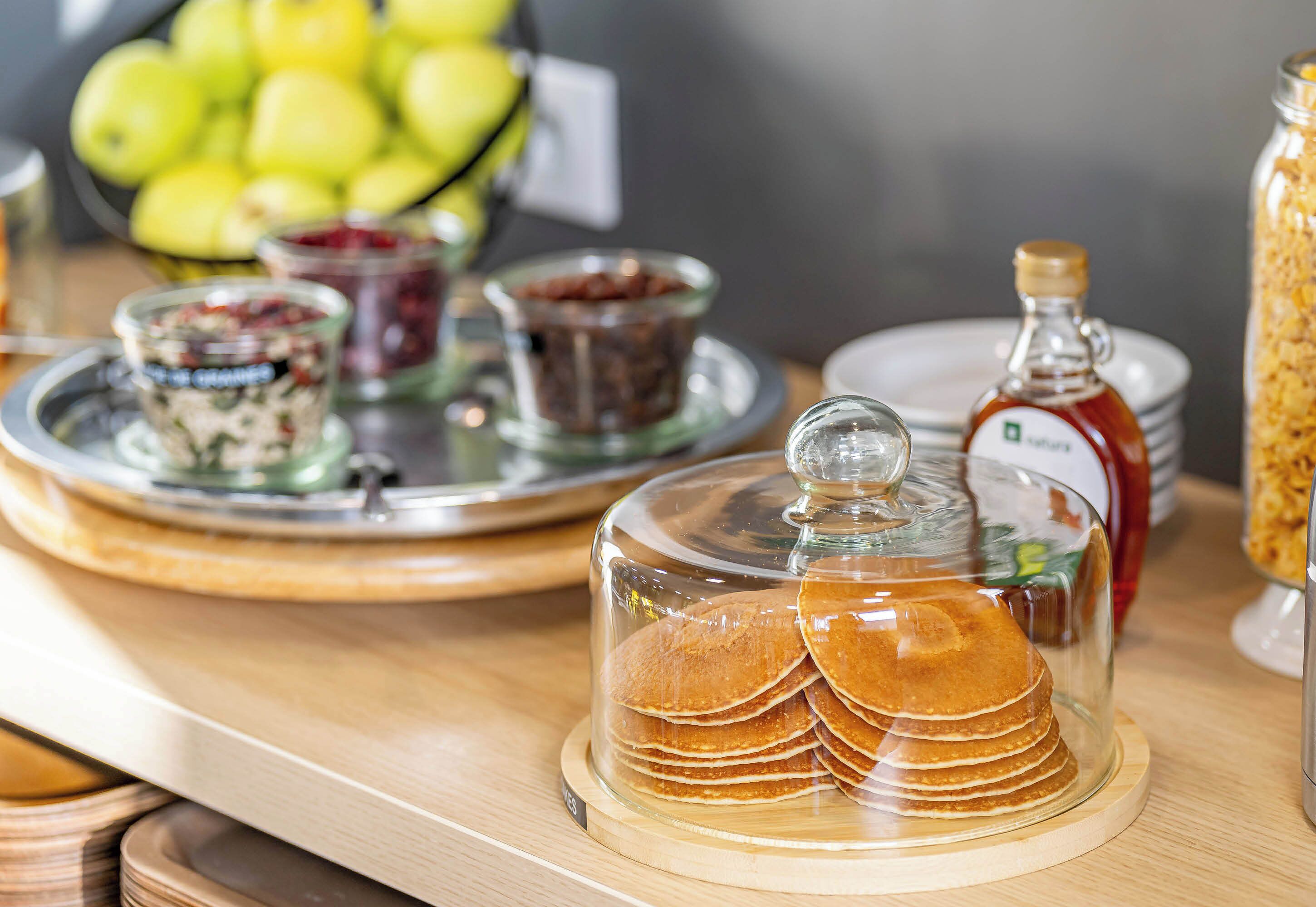 A breakfast buffet with pancakes, jams, and honey.