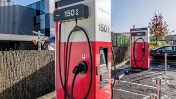 Två röda laddstationer för elfordon, prislapp 150 zł.