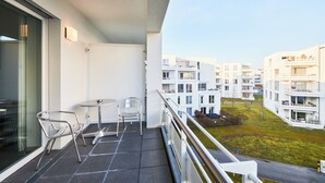 A balcony with a table and two chairs, overlooking a residential area with modern buildings. - ADAPT APARTMENT HOTEL Giessen (Giessen)