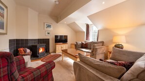Una sala de estar acogedora con chimenea, televisión y asientos cómodos.