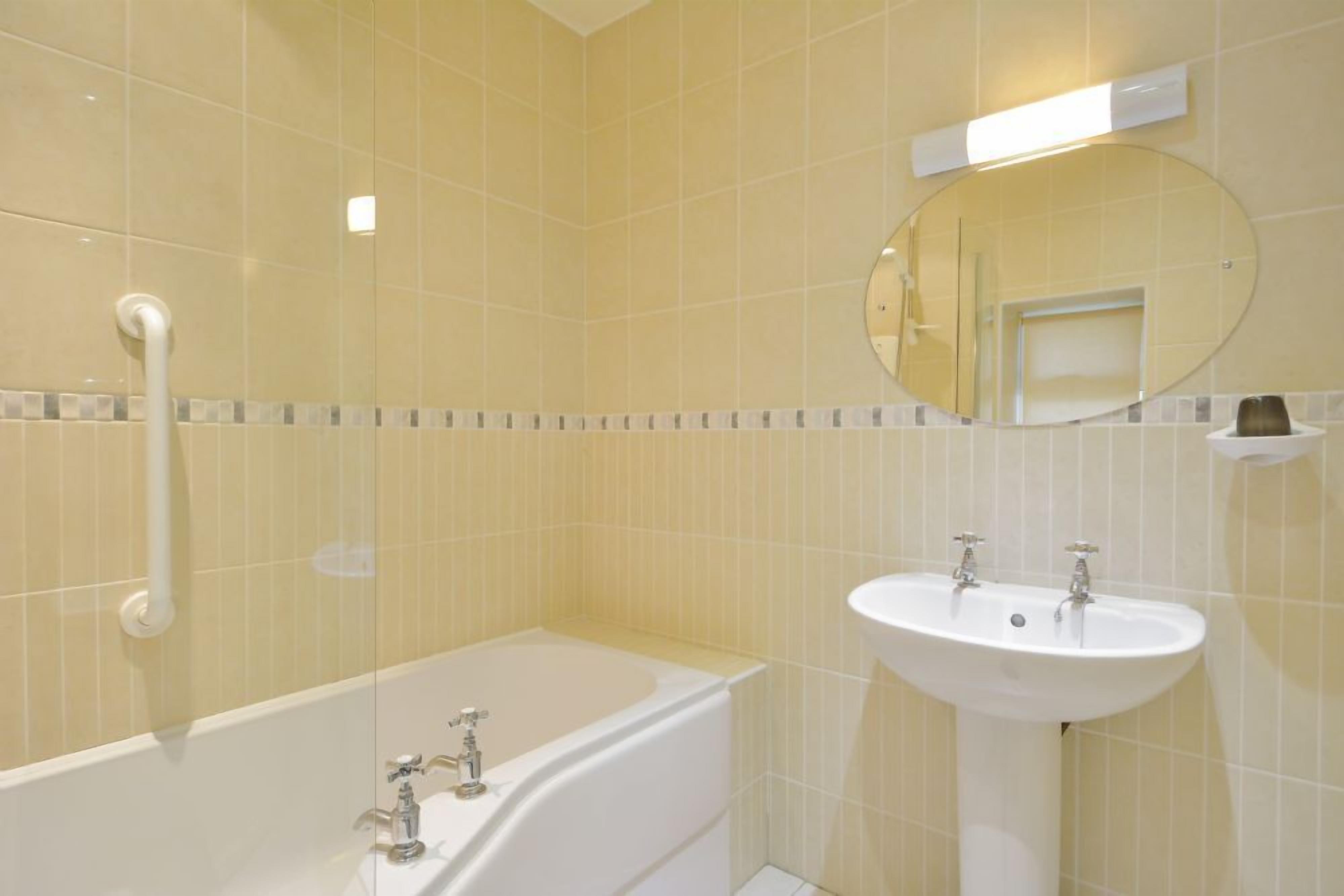 A bathroom with a bathtub, a sink, and a mirror.