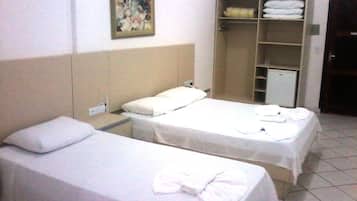 A hotel room with two single beds, a wardrobe, and a painting on the wall.