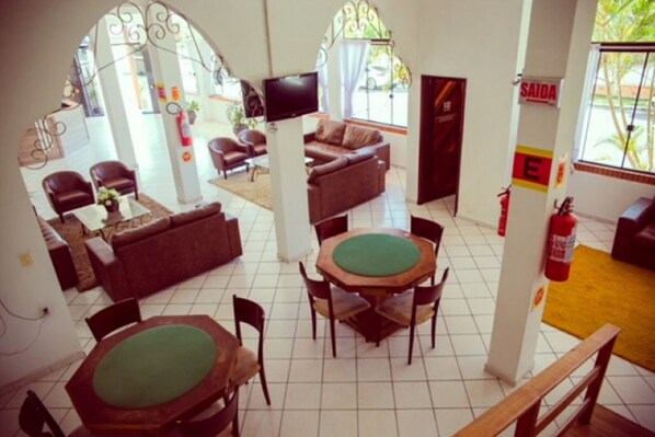 A spacious living area with a sofa, chairs, a coffee table, and a green table.