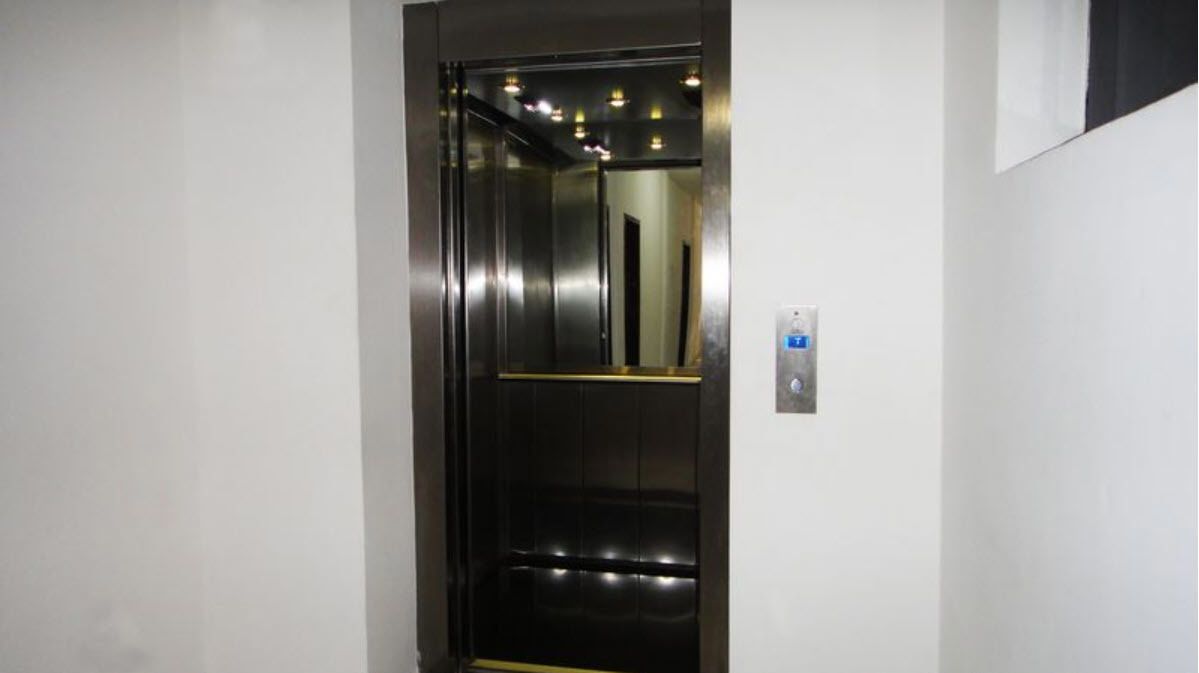 A modern elevator with a metallic finish and a control panel on the wall.