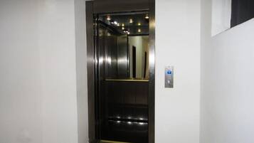 A modern elevator with a metallic finish and a control panel on the wall.