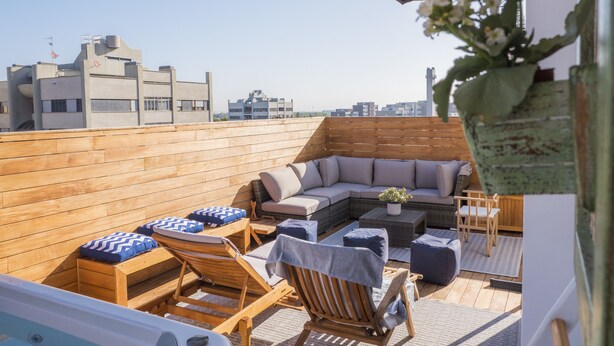 A rooftop terrace with wooden flooring, a sectional sofa, lounge chairs, and a potted plant. - Immerse Yourself in an Idyllic Situation (Bologna)