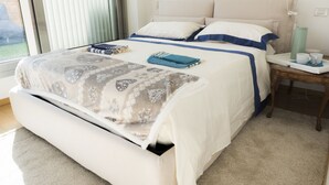 A neatly made bed with a patterned bedspread, pillows, and a blue blanket. There is a bedside table with a green water bottle, a cup, and a book. - Immerse Yourself in an Idyllic Situation (Bologna)