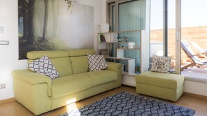 A living room with a green sofa, a matching ottoman, a patterned rug, and a bookshelf. - Immerse Yourself in an Idyllic Situation (Bologna)