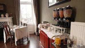 A breakfast bar with a coffee machine, a juice dispenser, and a variety of breakfast items. - Greenland House B&B (Castletown)