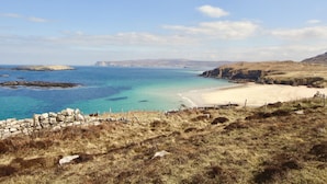 A coastal landscape with a sandy beach, rocky outcrops, and grassy terrain. - Greenland House B&B (Castletown)