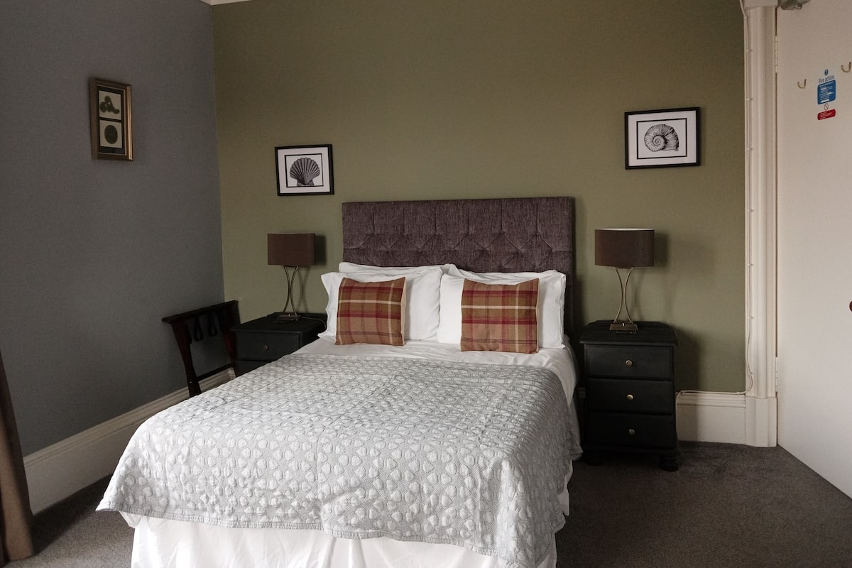 A neatly arranged bedroom with a large bed, two bedside tables, and a chair.