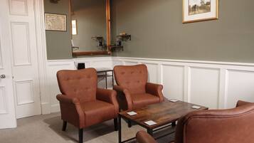 A room with two brown leather armchairs, a wooden coffee table, a large mirror, and a framed picture on the wall.