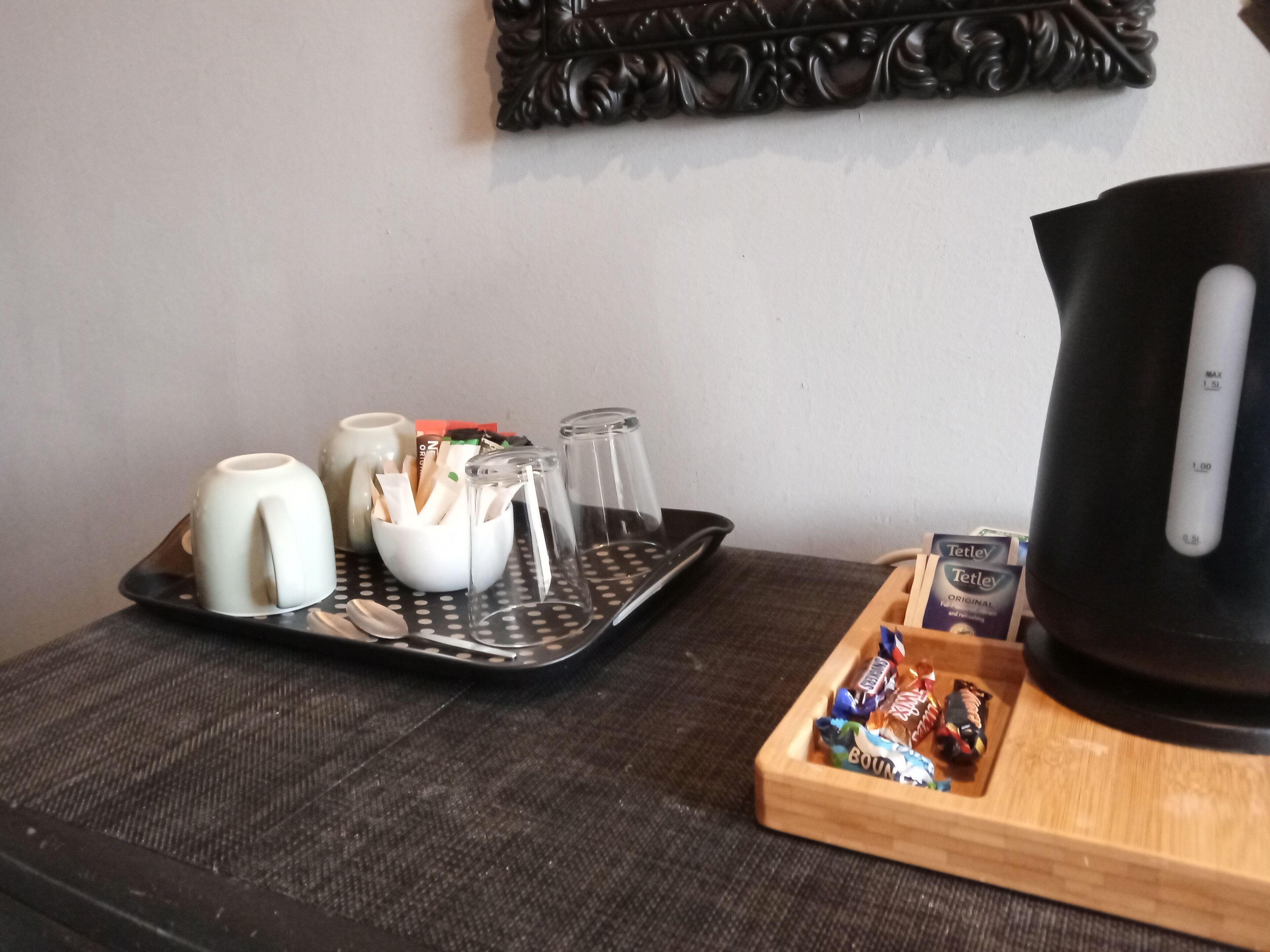 Un plateau avec des tasses, une théière et une boîte de thé Tetley, posé sur une table.