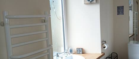 A bathroom with a white sink, a toilet, a towel rack, and a window.