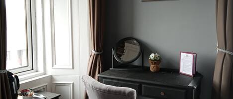 A room with a desk, chair, and a framed picture on the wall.