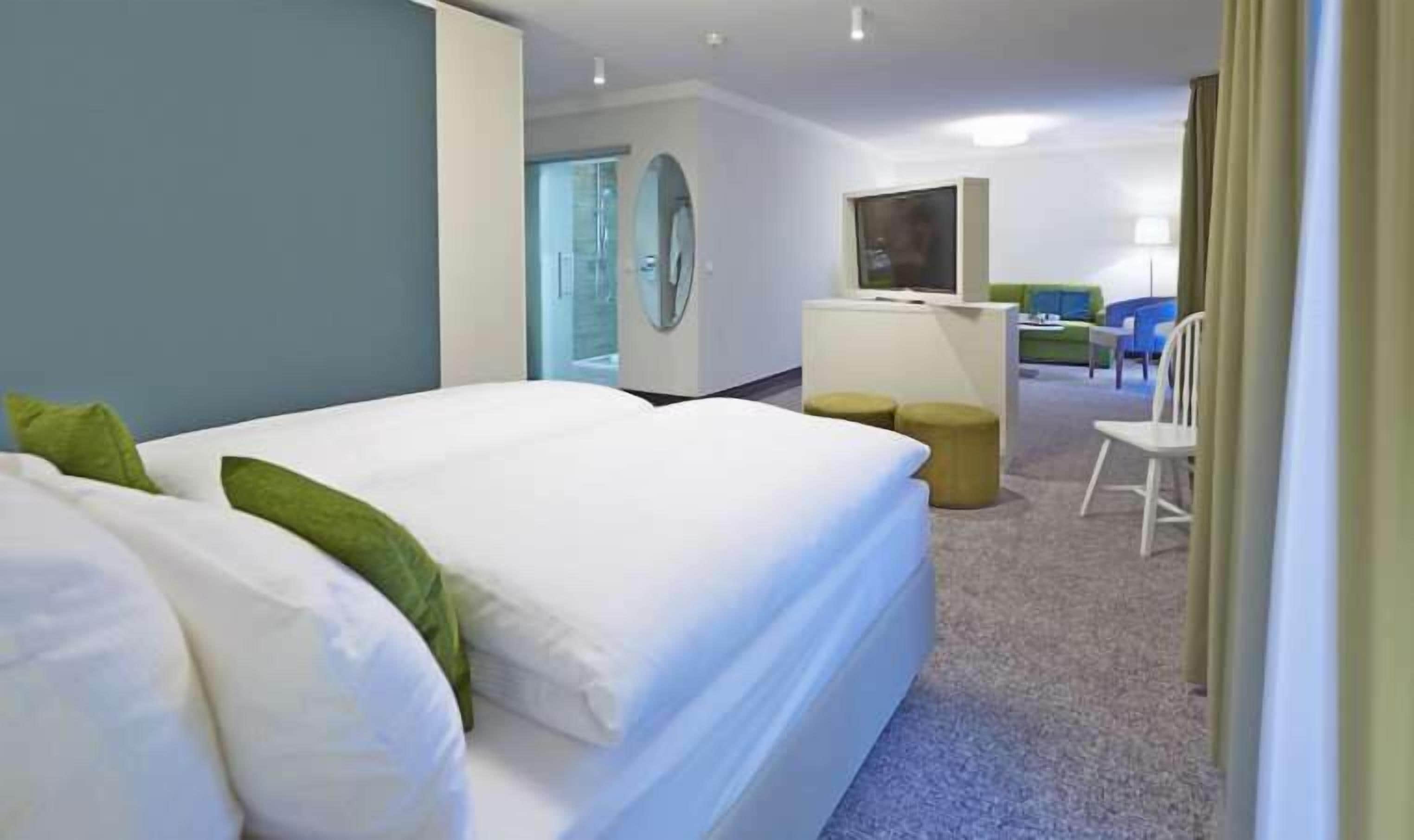 Una habitación de hotel con una cama grande, un escritorio y un televisor.