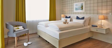 A neatly arranged hotel room with a bed, bedside table, lamp, and a chair.