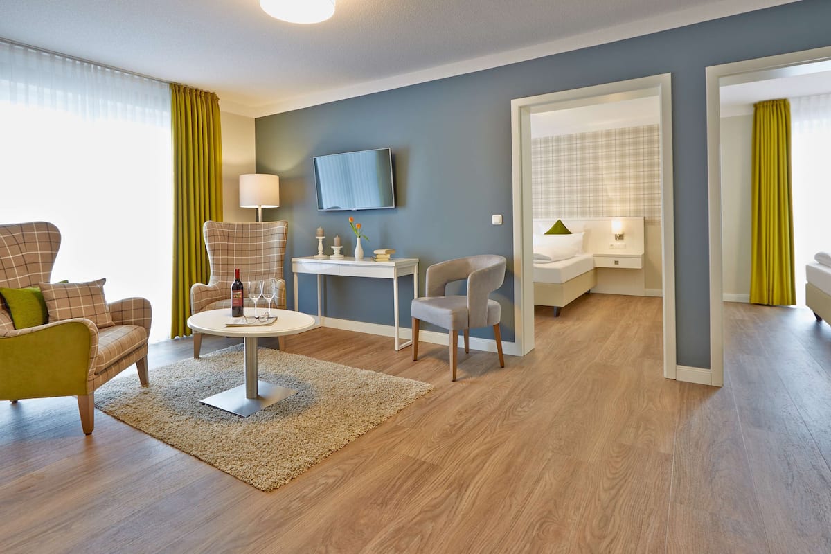 Una sala de estar moderna con sofá, sillón, mesa de centro y televisor en la pared.
