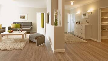 A modern living room with a sofa, coffee table, and ottoman, a dining area with a table and chairs, and a walk-in closet with shelves and a mirror.