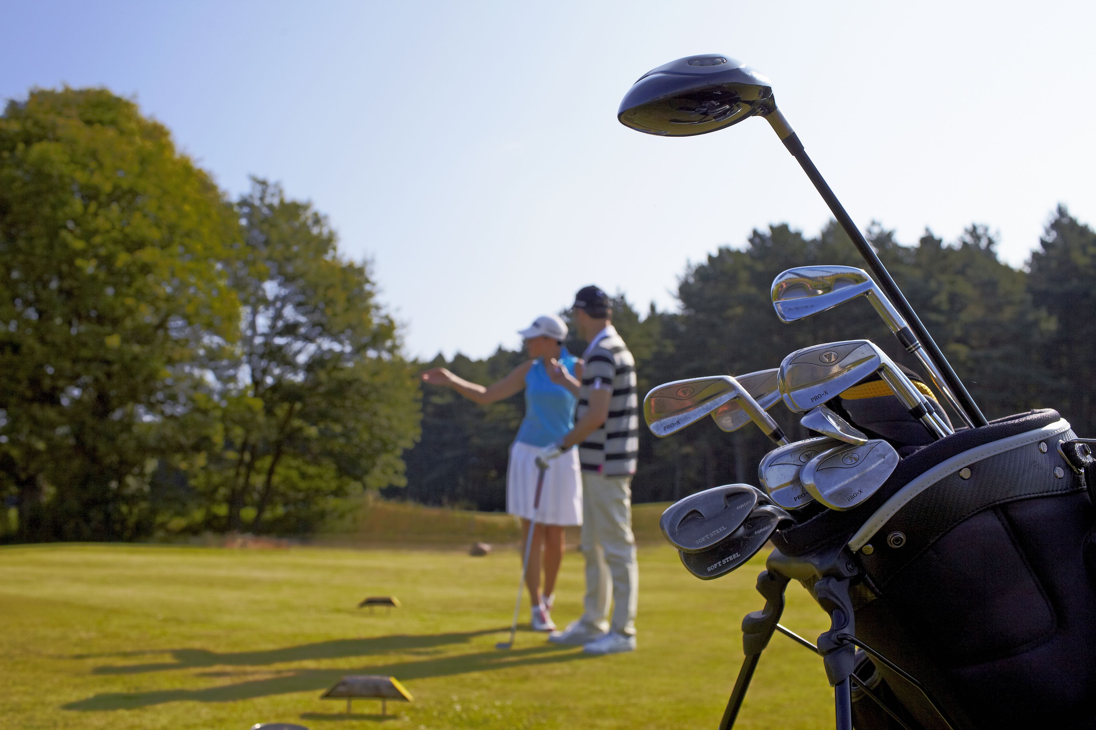 En golftaske med flere køller på en golfbane.