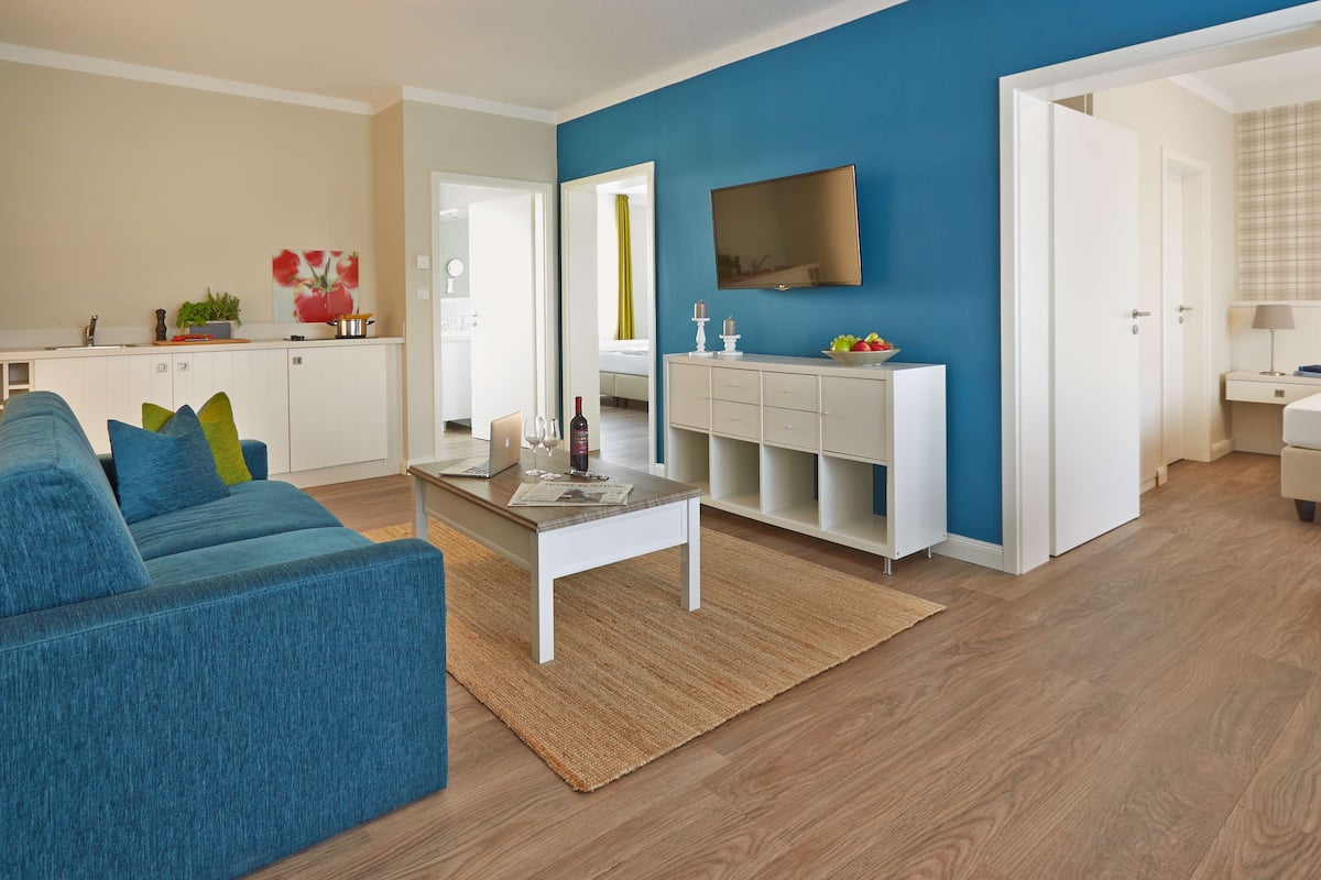 Una sala de estar moderna con una pared azul de acento, un sofá blanco y una mesita de centro.