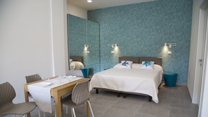 A hotel room with a bed, bedside tables, a dining table with chairs, and a large mirror.