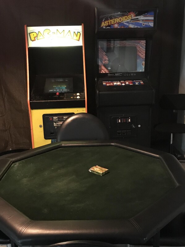 Un espace de jeux équipé de deux bornes d’arcade, l’une portant l’inscription « PAC-MAN » et l’autre « ASTEROIDS ».