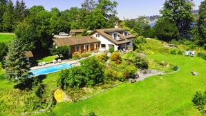 Une grande maison avec une piscine, entourée d’une végétation luxuriante et offrant une vue dégagée sur le ciel.