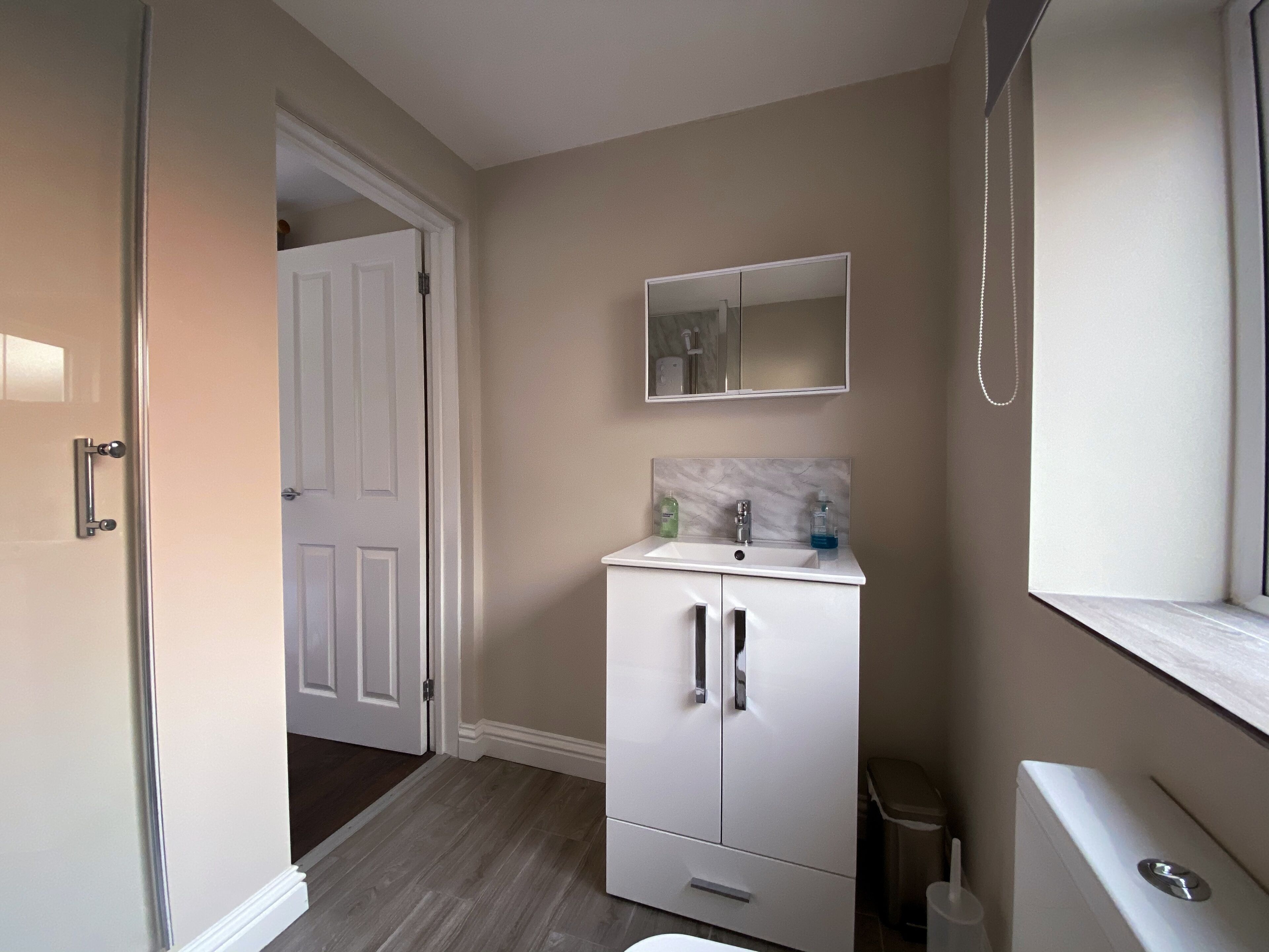 A compact bathroom with a white vanity, a mirror above the sink, and a toilet.
