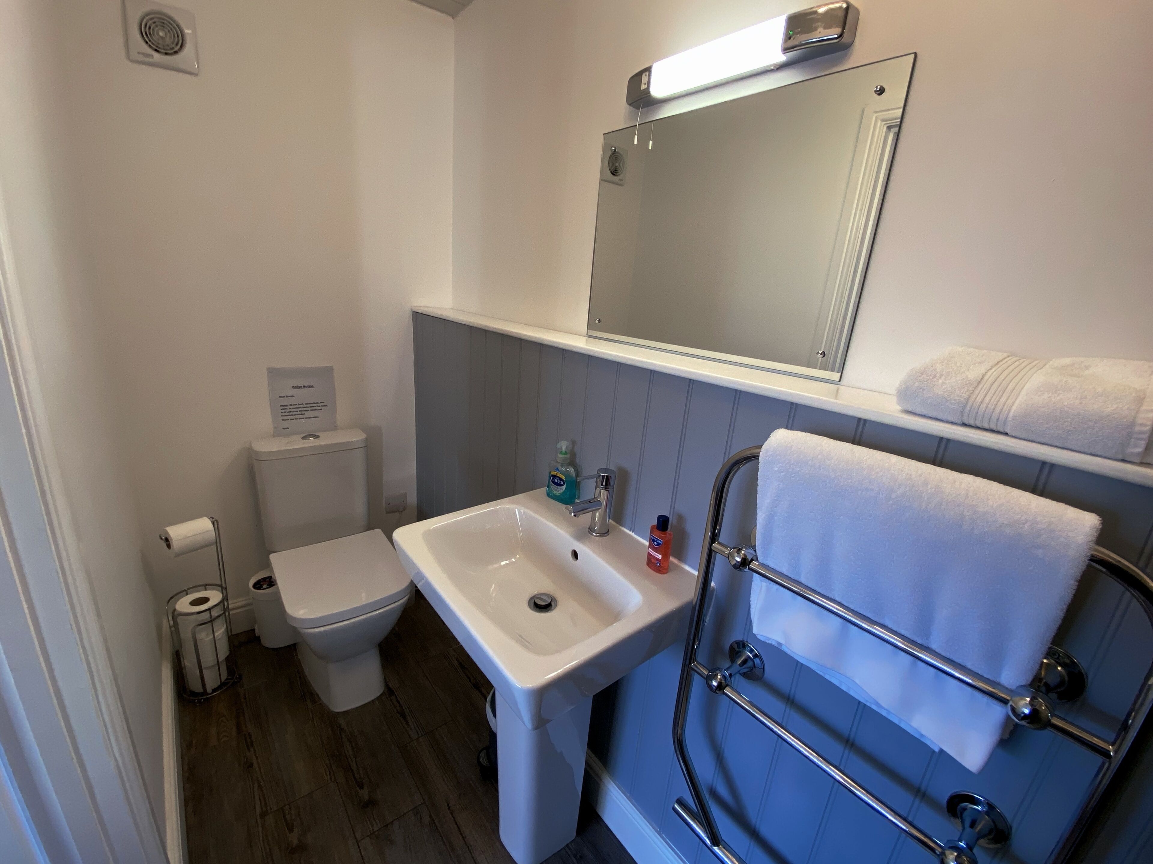A compact bathroom with a white toilet, a white sink, and a blue towel rack.