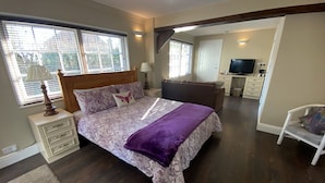 Ein Schlafzimmer mit einem großen Bett, einem Schreibtisch, einem Stuhl und einem Fernseher.